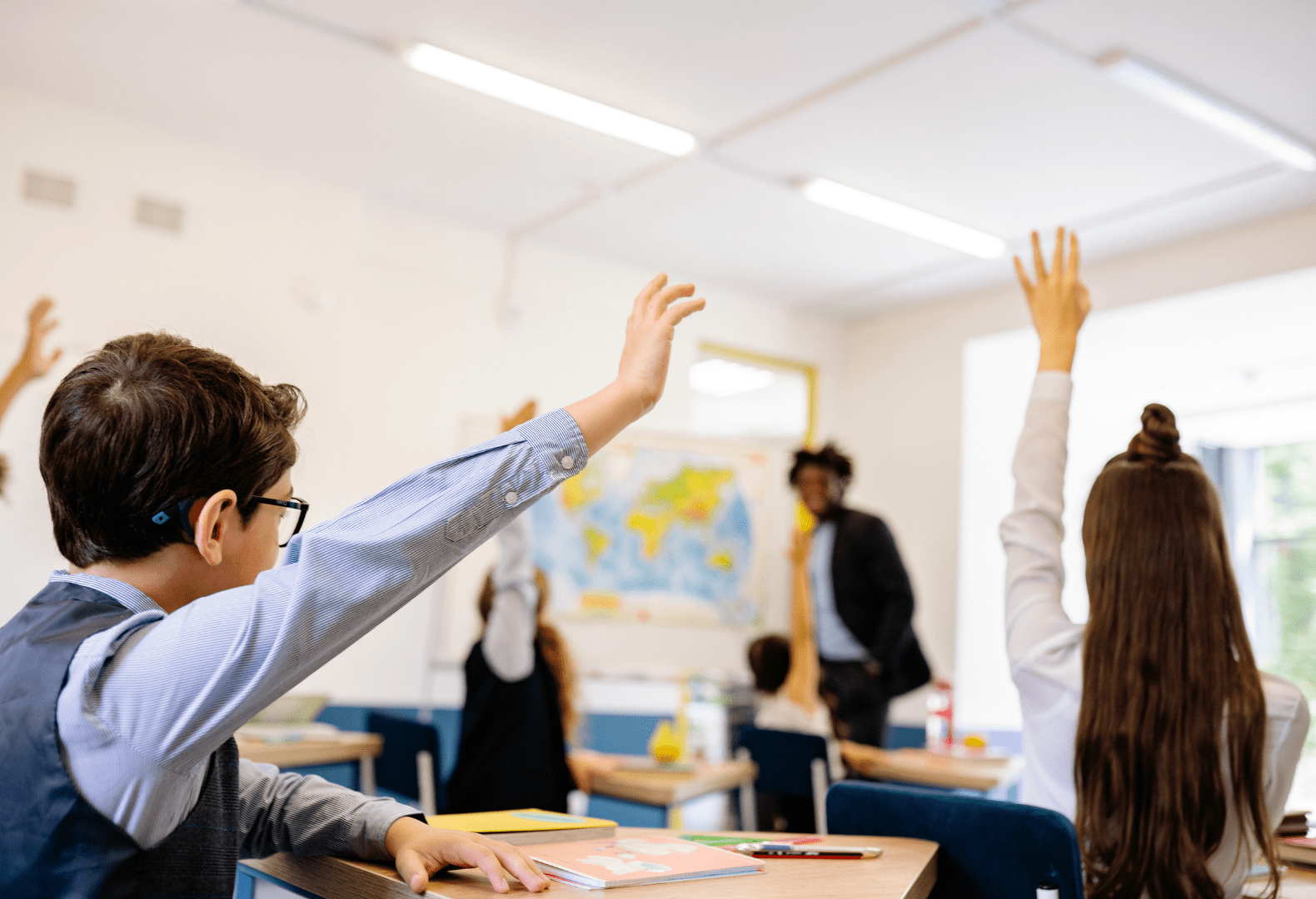 a group of students in the classroom raising their hands