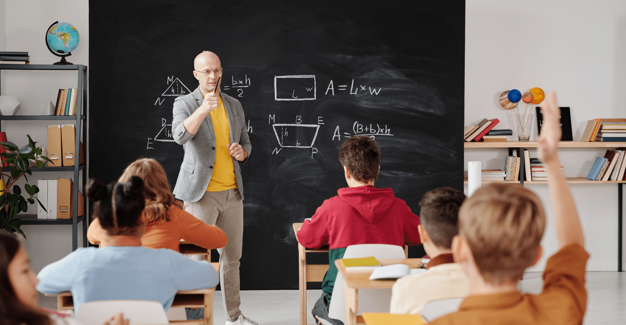 a person standing in front of a blackboard with students sitting at desks