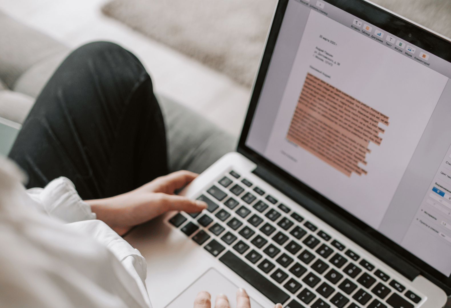 a person sitting on a couch writing cover letter on a laptop