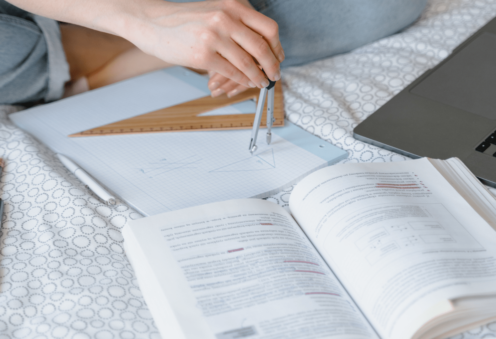 a person sitting on a bed with books and a laptop