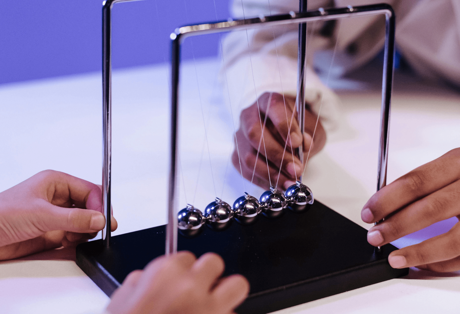 two children playing with a newton's cradle on a table